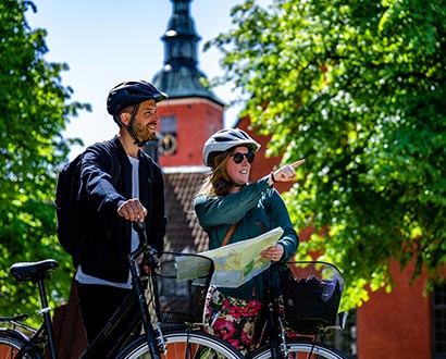 Två cyklister pekar på karta utanför Halmstads slott